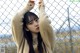 A woman standing behind a chain link fence.