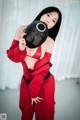 A woman in a red outfit holding a black mask.