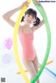 A young girl in a pink bathing suit holding a hula hoop.