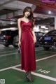 A woman in a red dress standing in a parking garage.