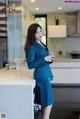 A woman standing in a kitchen holding a glass of water.