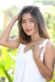 A woman in a white tank top posing for a picture.