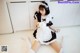 A woman in a maid outfit is sitting on the floor.