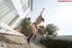 A woman jumping in the air in front of a house.