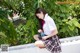 A young woman in a school uniform sitting on a wall.