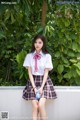 A woman in a school uniform sitting on a wall.