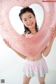 A young woman holding a pink heart shaped inflatable ring.