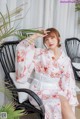 a woman sitting on a chair wearing a pink kimono