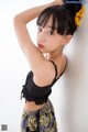 A young girl leaning against a wall with a flower in her hair.