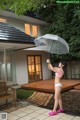 A woman in a pink bikini holding an umbrella.