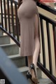 A woman in a brown dress is standing on some stairs.