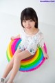 A little girl sitting on top of a rainbow shaped pool float.