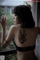 A woman with a tattoo on her back looking out a window.