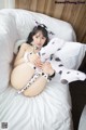 A woman in a cow costume laying on a bed.