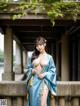 A woman in a blue kimono posing for a picture.