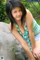 A young woman sitting on a rock in the woods.