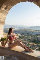 A woman in a bikini sitting on a ledge.