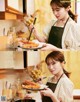 A woman in an apron holding a plate of food with chopsticks.