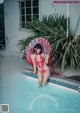 A woman in a red bikini sitting on the edge of a pool.