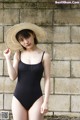 A woman in a black swimsuit and a straw hat.