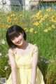 A woman in a yellow dress sitting in a field of flowers.