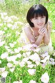 A young woman sitting in a field of flowers.