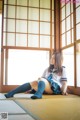 A woman in a school uniform sitting on the floor.