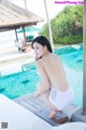 A woman in a white bathing suit sitting by a pool.