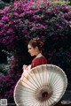 A woman in a red dress holding a white umbrella.