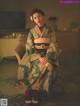 A woman in a kimono sitting on a chair.