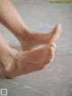 A close up of a person's bare feet on a tiled floor.