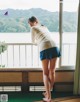 A woman standing in front of a window looking out at the water.