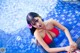 A woman in a red bikini sitting in a swimming pool.