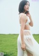 A woman in a white dress standing in a field.