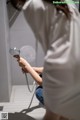 A woman in a white shirt is holding a shower head.