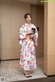 A woman in a kimono standing in a hallway holding a book.