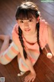 A young woman sitting on the floor with a pom pom.