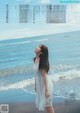 A woman in a white dress standing on a beach.