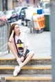 A woman sitting on the steps of a city street.