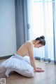 A young ballerina in a white tutu sitting on the floor.