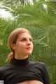 A woman in a black top standing in front of a palm tree.