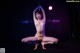 A naked woman is sitting on a pole in the dark.