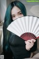 A woman with blue hair holding a red and white fan.