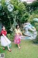 Two young women are playing with soap bubbles in the yard.