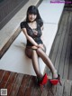 A woman sitting on a white bench wearing black stockings and red shoes.