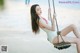 A woman in a white bathing suit sitting on a swing.