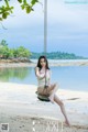 A woman sitting on a swing on a beach.