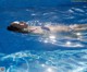 A woman floating in a swimming pool with her eyes closed.