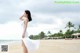 A woman in a white dress standing on a beach.