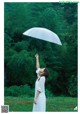 A woman in a white dress holding an umbrella in the rain.